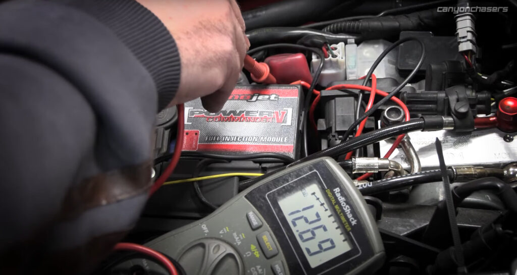 Multimeter checking motorcycle battery voltage