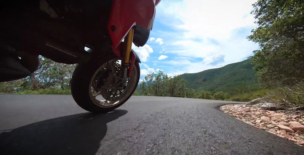 Motorcycle forks compressing in a downhill corner