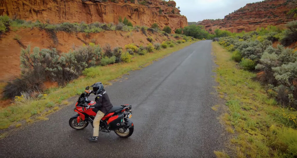 Motorcycle performing a U-turn on a narrow road.