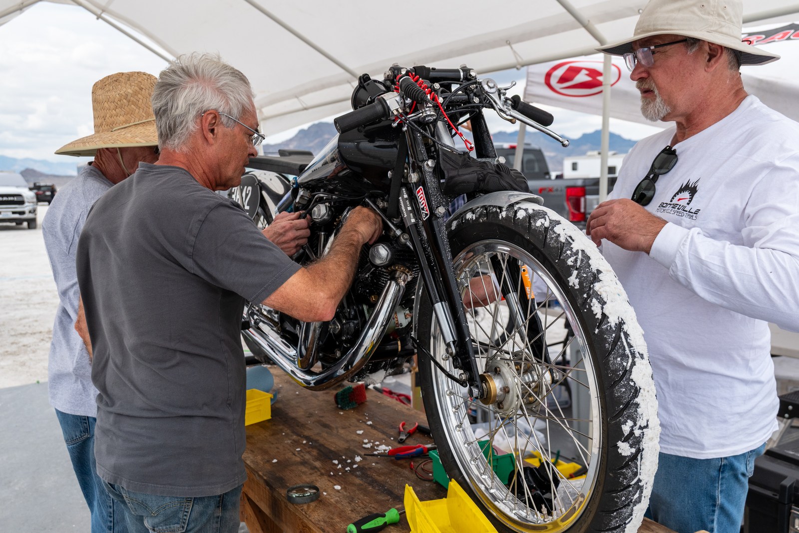 Two men working together on a vintage motorcycle in the Bonneville pits