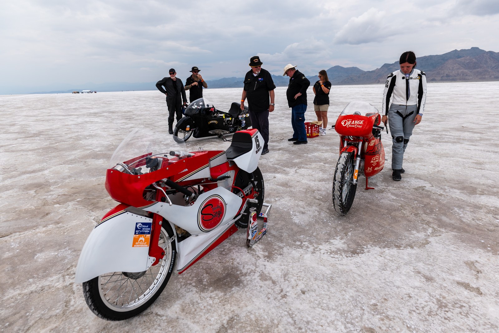 Two small-bore Honda race bikes staged on the Bonneville salt with their crews