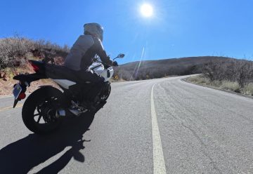 A motorcycle leaning into a sunlit canyon corner