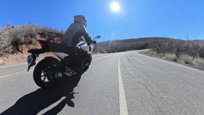 A motorcycle leaning into a sunlit canyon corner