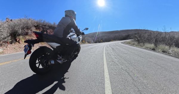 A motorcycle leaning into a sunlit canyon corner