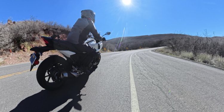 A motorcycle leaning into a sunlit canyon corner