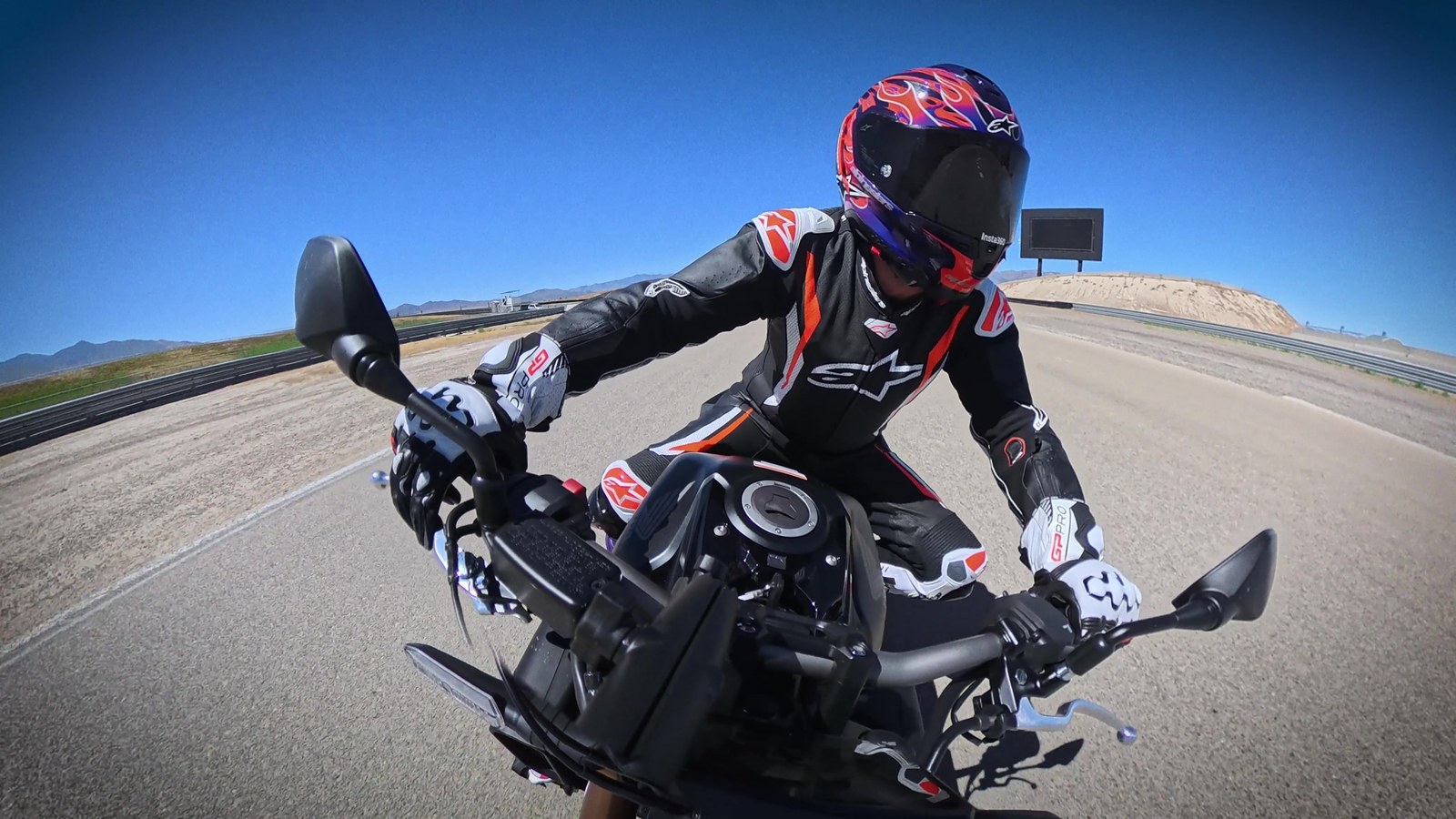 Rider leaned into a corner on a black Honda CB650R at a racetrack under a clear blue sky