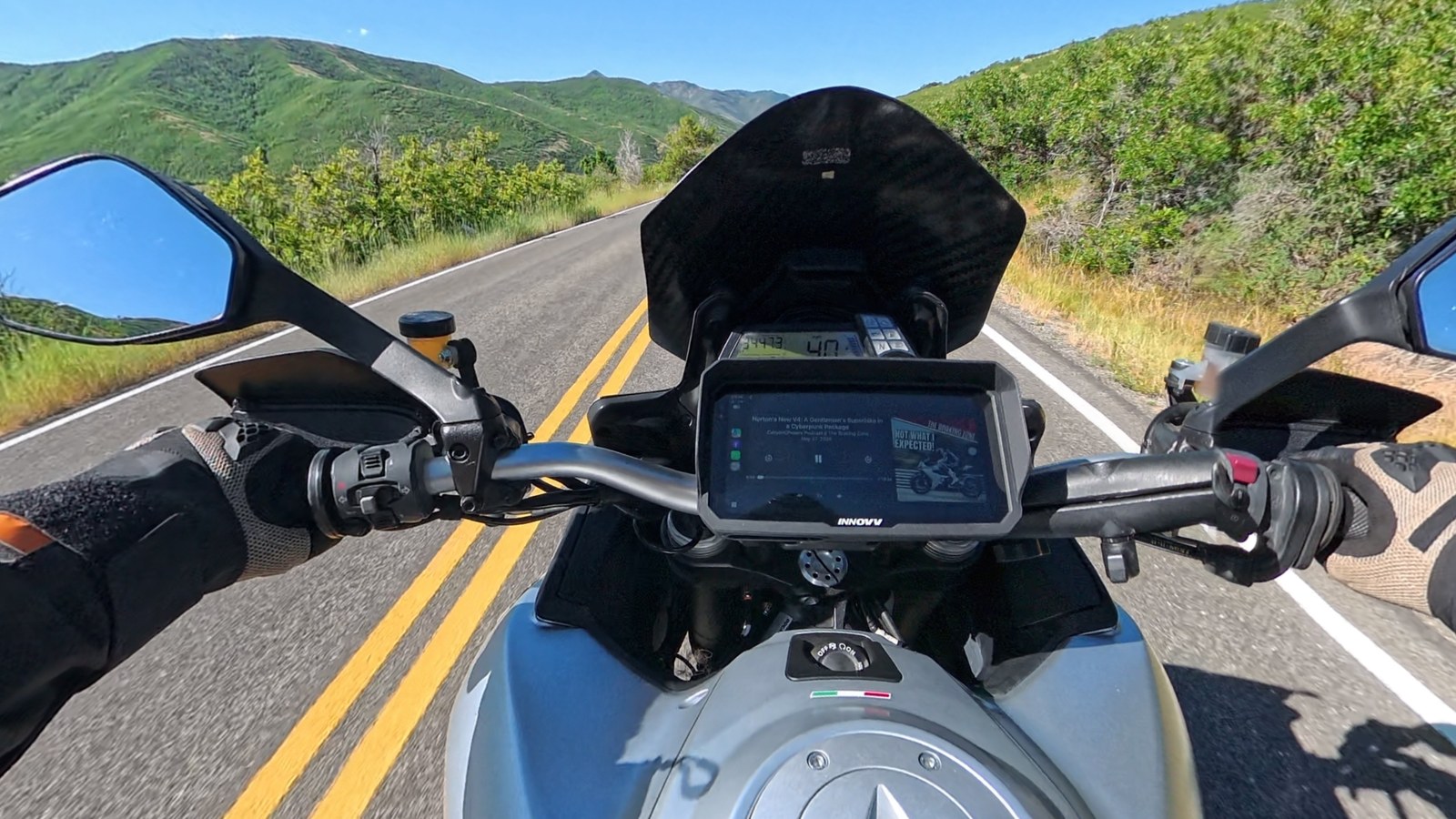 The INNOVV N3 display mounted on a motorcycle's handlebars running Apple CarPlay on a canyon road