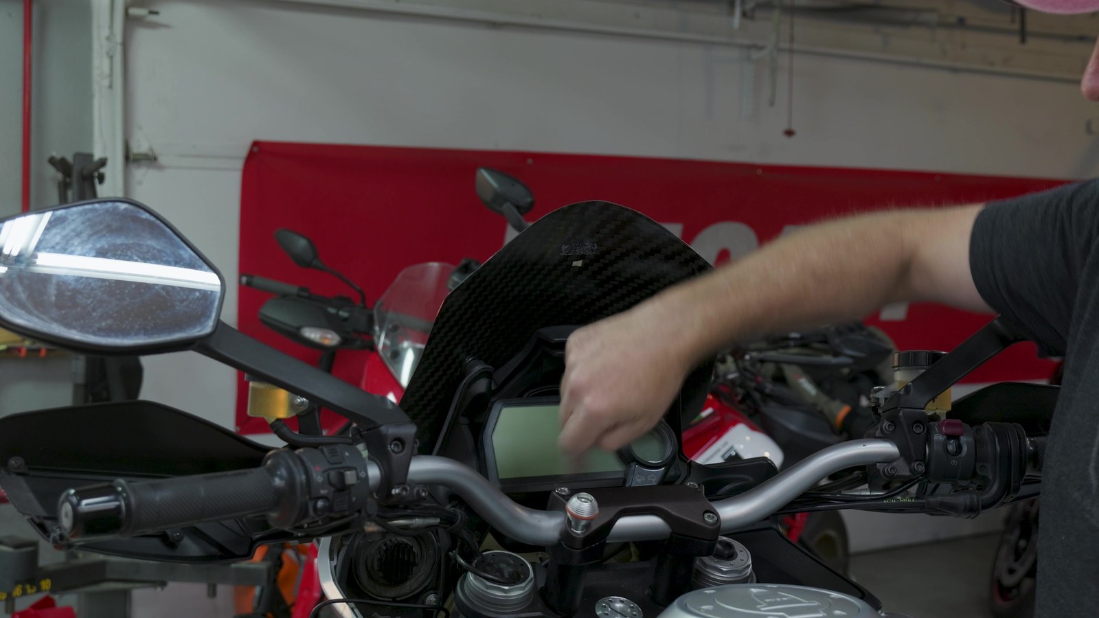 Hands mounting the INNOVV N3 display onto the motorcycle handlebar mount in a garage