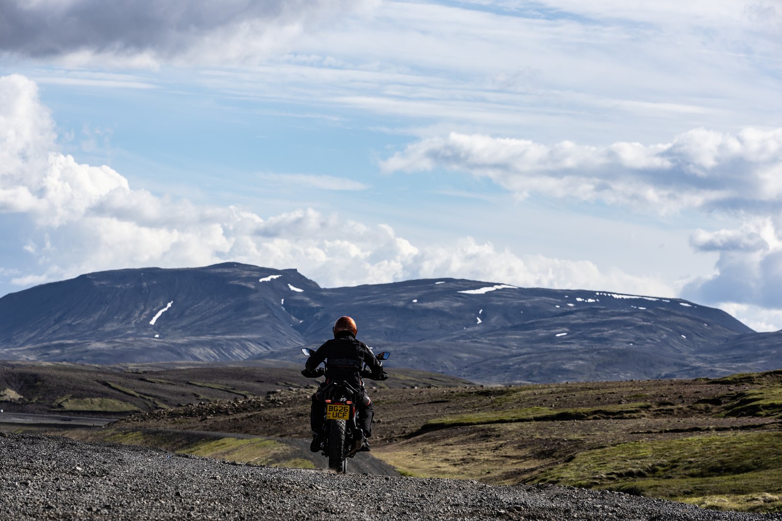 2026 Norton Atlas riding away on a gravel road toward snow-capped Icelandic mountains