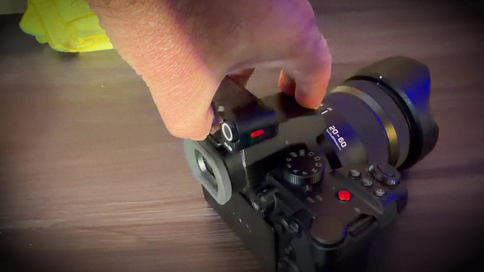 A hand sliding the Insta360 Mic Pro receiver onto the hot shoe of a professional mirrorless camera