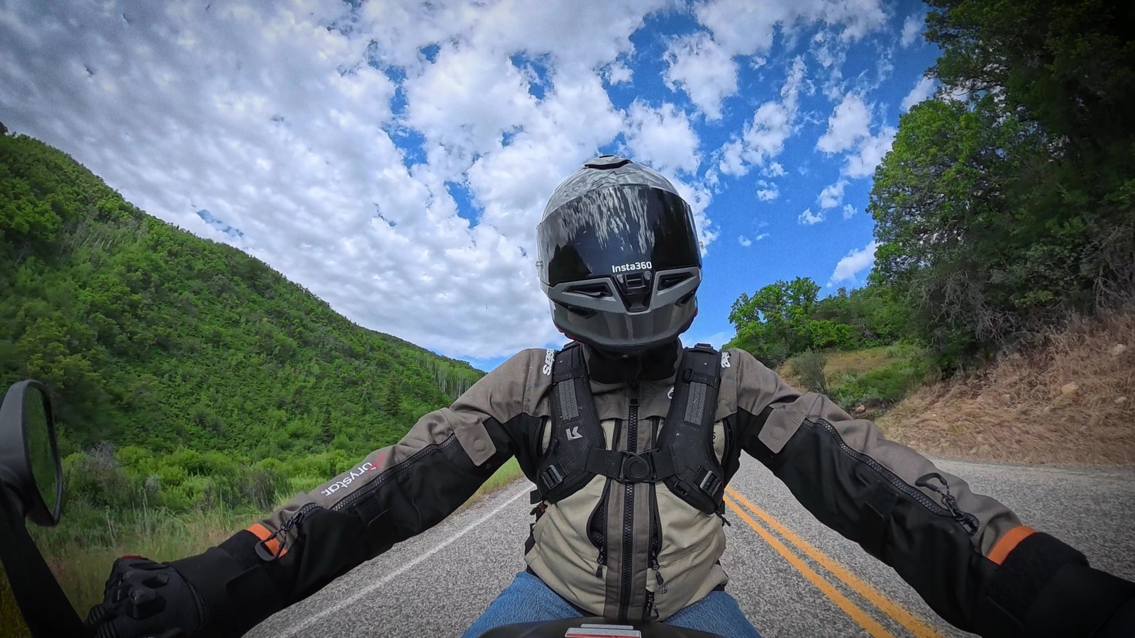Point-of-view riding shot on a canyon road with a rider's arms outstretched to the bars