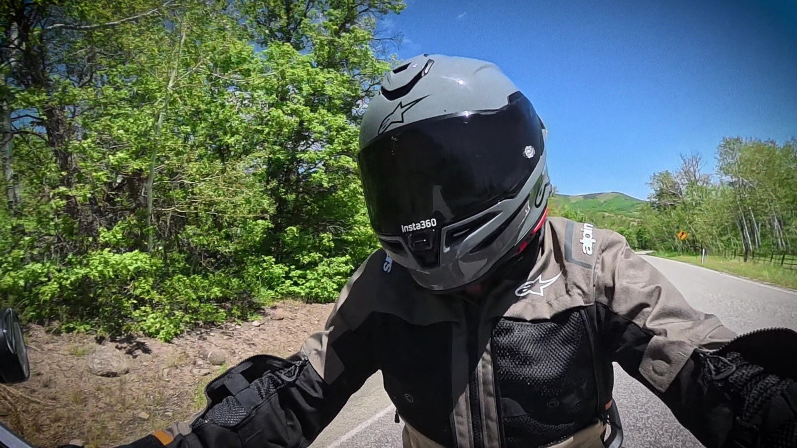 Riding a motorcycle down a road lined with aspen trees