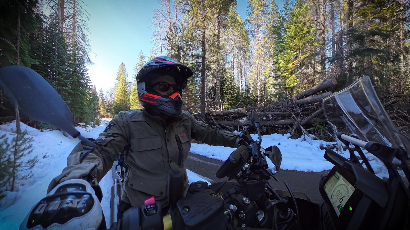 Riding a motorcycle on a shaded mountain road near lingering snow