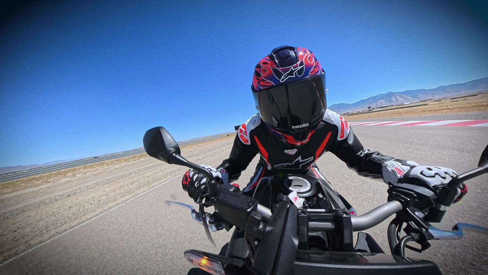 Point-of-view shot riding a naked motorcycle on a racetrack under a blue sky
