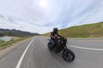 A rider on a black Triumph Trident 660 on a scenic reservoir road