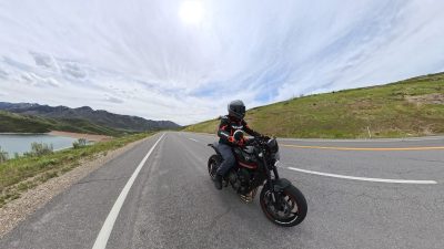 A rider on a black Triumph Trident 660 on a scenic reservoir road