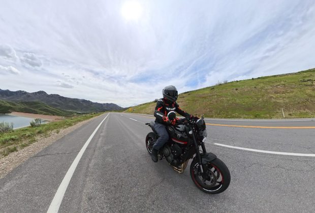 A rider on a black Triumph Trident 660 on a scenic reservoir road