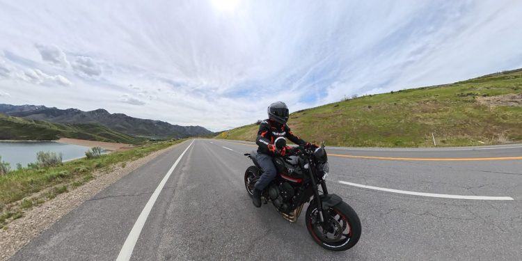A rider on a black Triumph Trident 660 on a scenic reservoir road