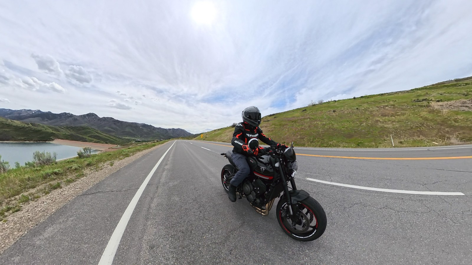 A rider on a black Triumph Trident 660 on a scenic reservoir road