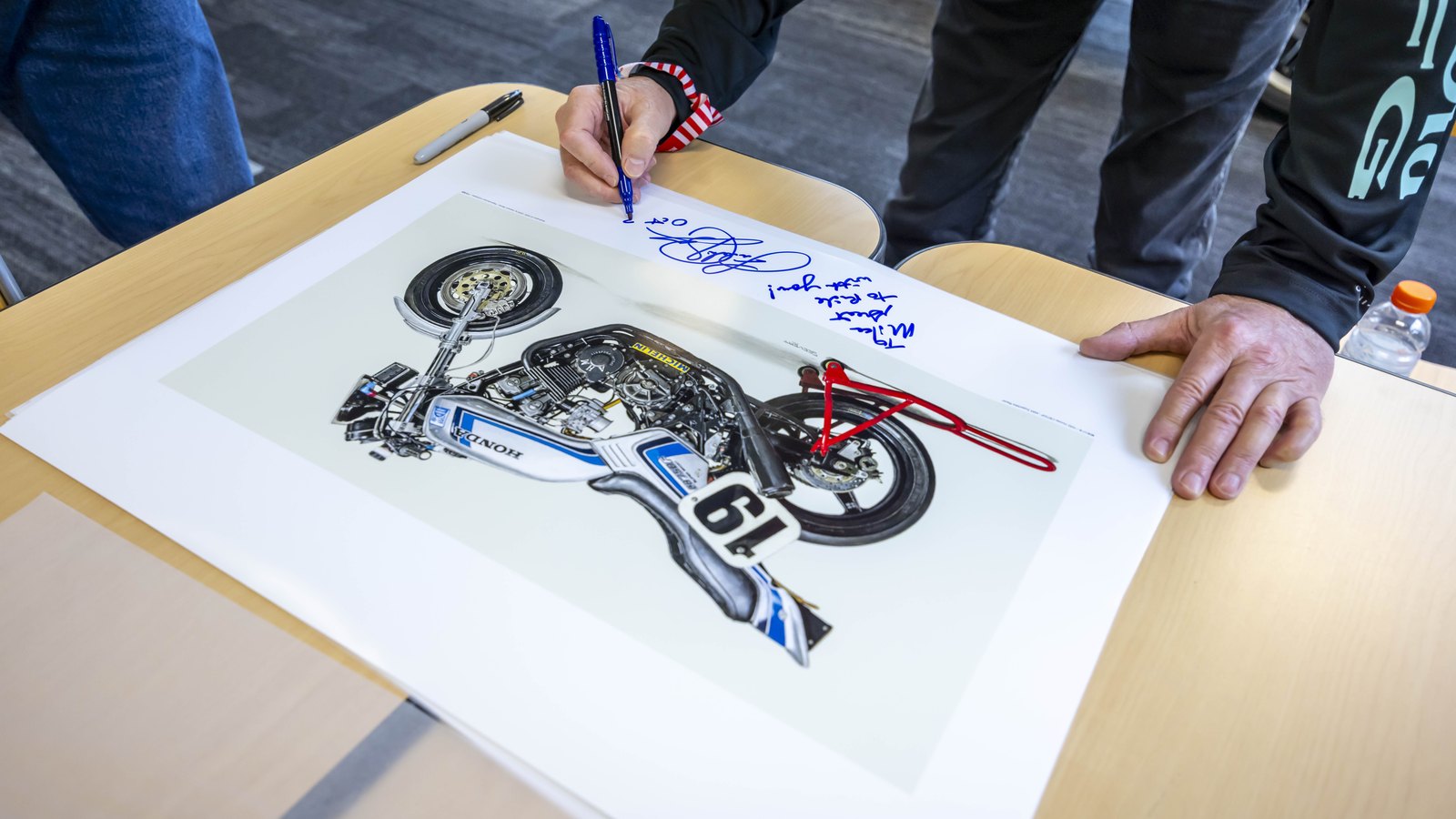 Freddie Spencer signing a print of the number 19 CB750F at the launch.
