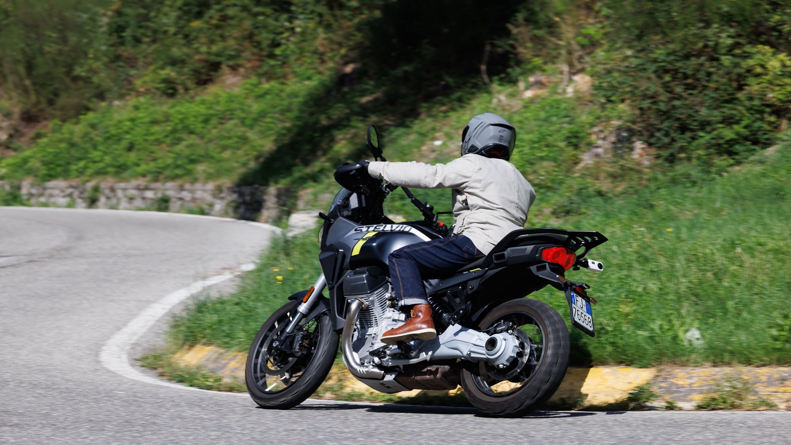 A rider on a Moto Guzzi exiting a tight uphill hairpin