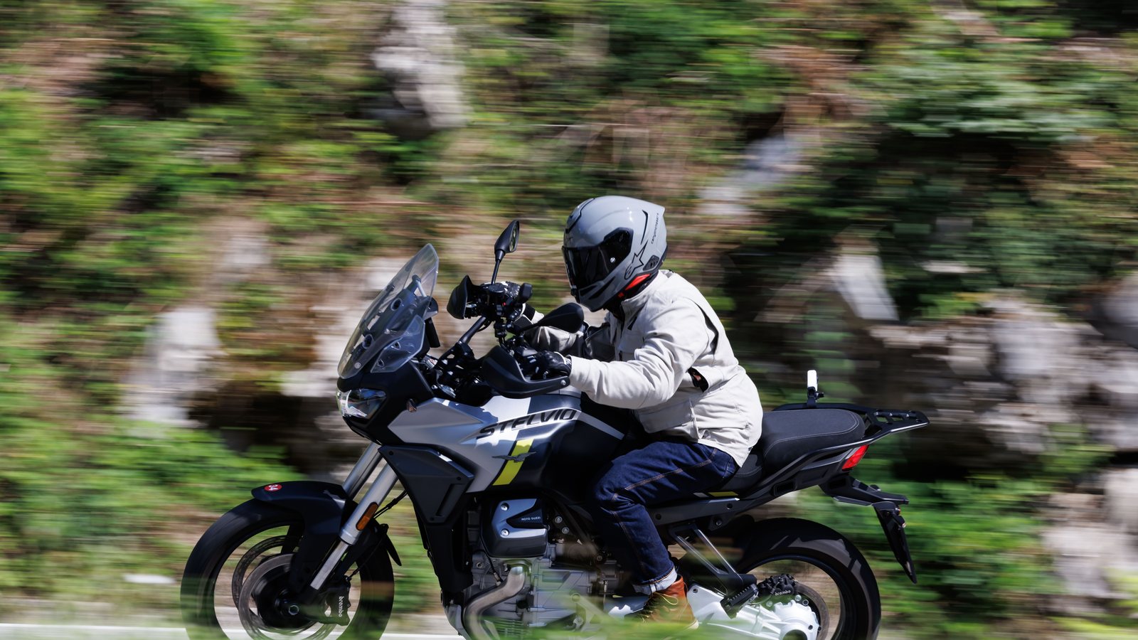 A rider on a Moto Guzzi at speed on a mountain road